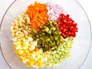 overhead view of macaroni salad ingredients in glass bowl