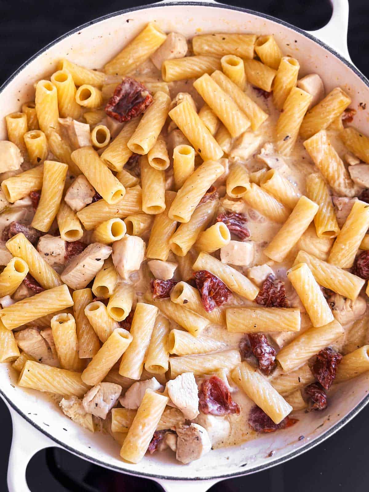 overhead view of cooked tuscan chicken pasta in white cast iron skillet