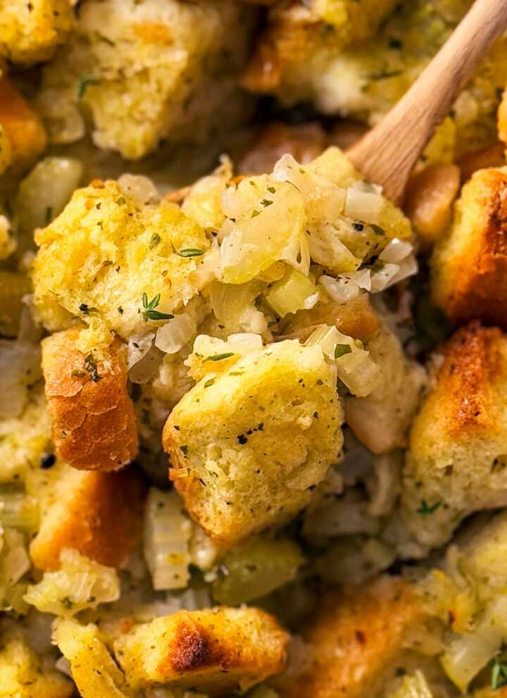 overhead close up photo of wooden spoon scooping stuffing from casserole