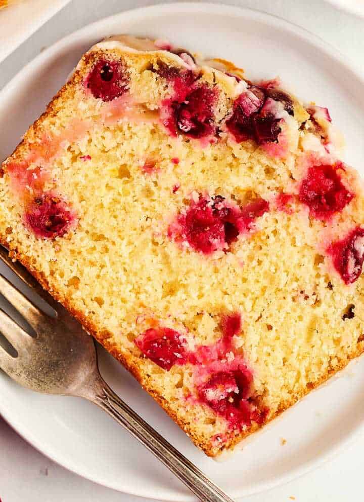overhead view of cranberry orange bread slice on white plate with fork