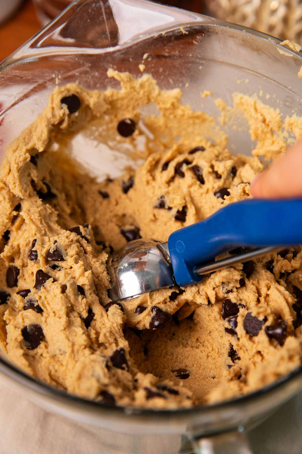 Using a cookie scoop to scoop chocolate chip cookie dough from a bowl.
