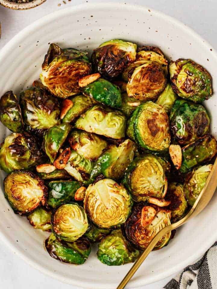 overhead view of roasted Brussels sprouts in a white bowl with a spoon