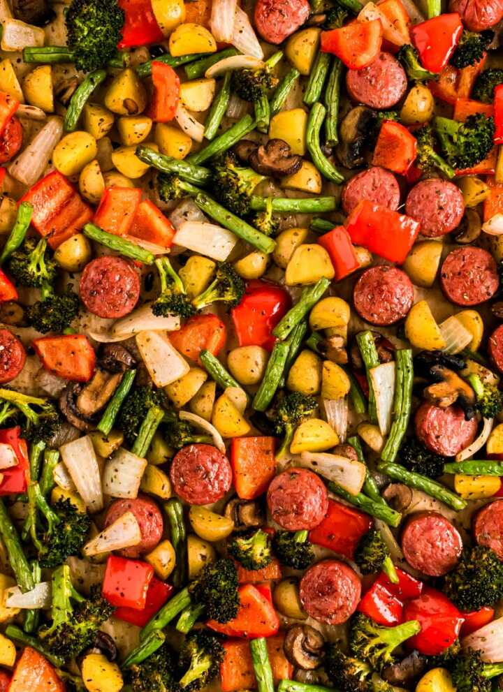overhead view of roasted vegetables and sausage slices on sheet pan