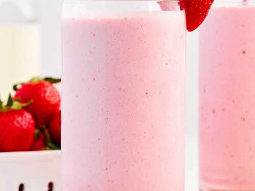 frontal view of strawberry smoothie in glass decorated with fresh strawberries