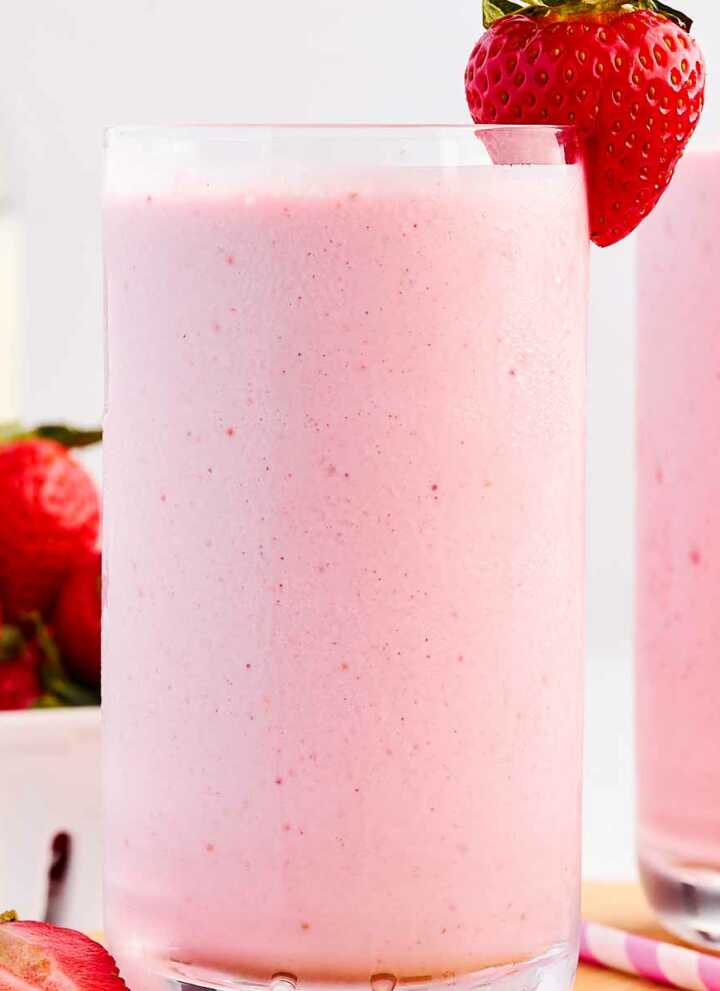 frontal view of strawberry smoothie in glass decorated with fresh strawberries
