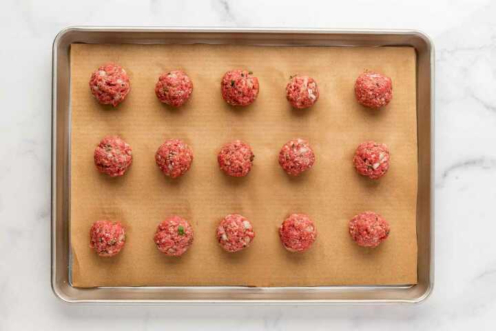overhead view of uncooked meatballs on baking sheet
