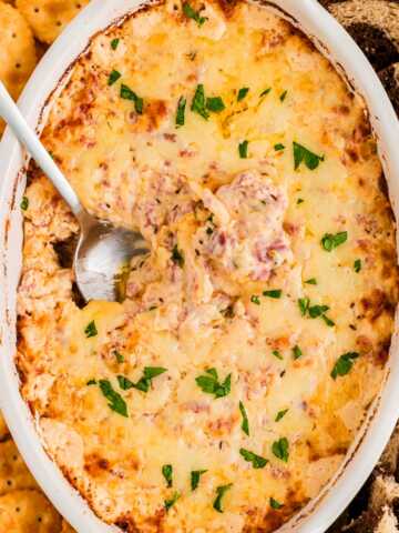overhead view of hot reuben dip in white baking dish with spoon stuck in