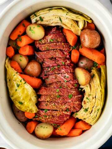 overhead view of corned beef, cabbage and vegetables in slow cooker insert