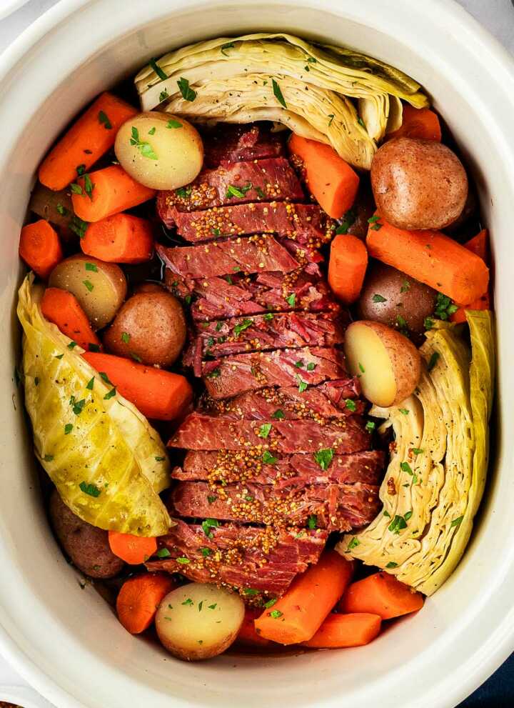 overhead view of corned beef, cabbage and vegetables in slow cooker insert
