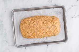 overhead view of uncooked chicken meatloaf on lined sheet pan