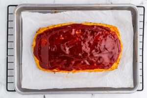 overhead view of baked glazed chicken meatloaf on lined sheet pan