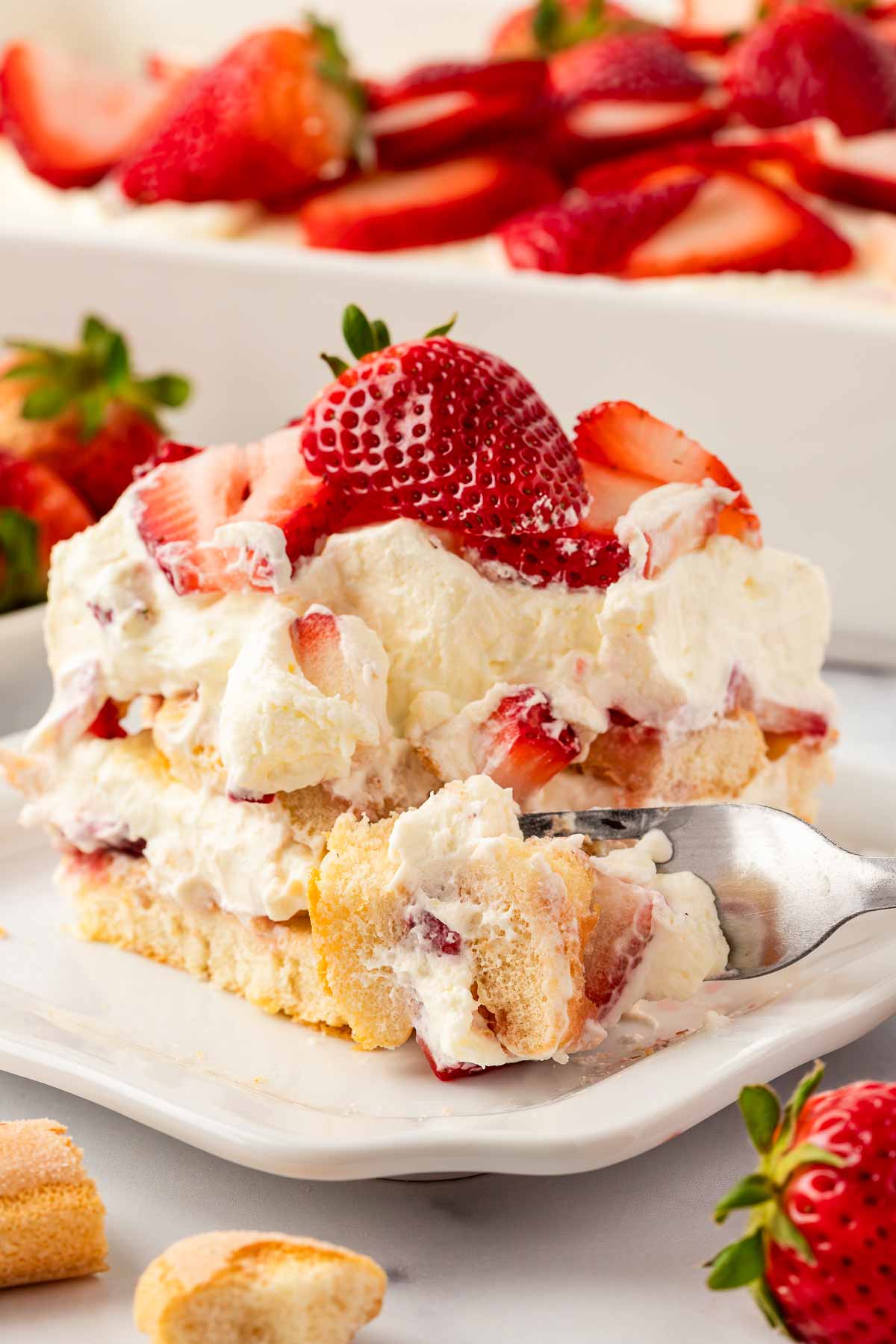 fork taking a bite from strawberry tiramisu on plate