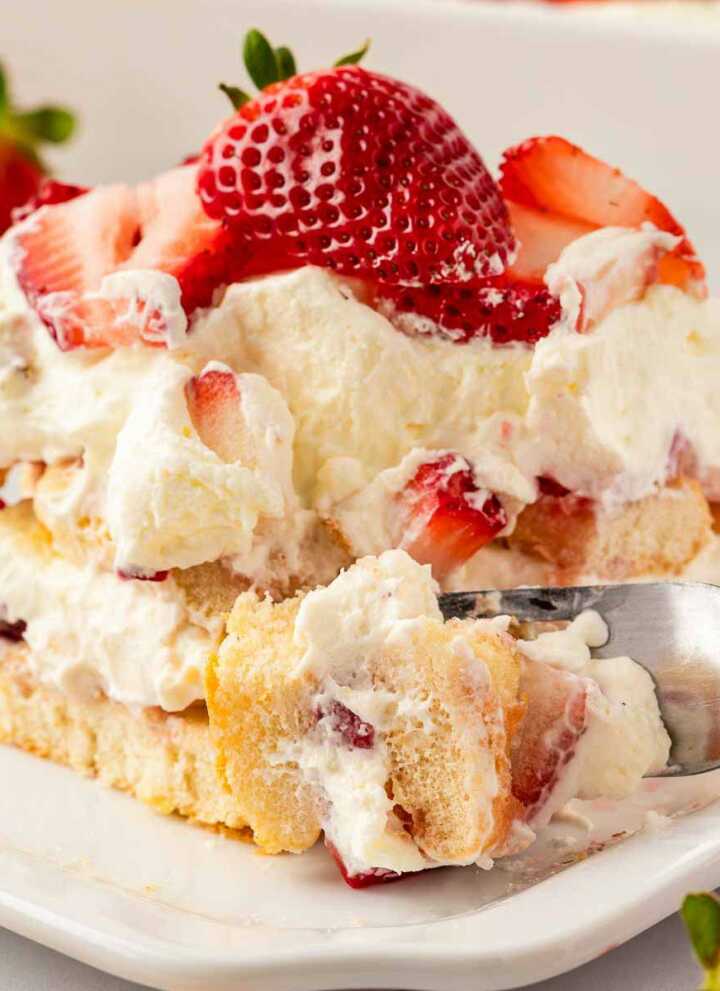 fork taking a bite from strawberry tiramisu on plate