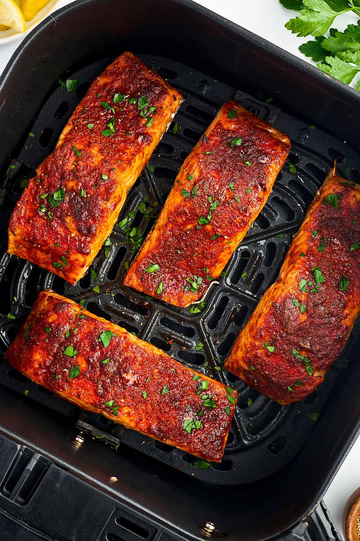 overhead view of four air fried salmon fillets in air fryer basket