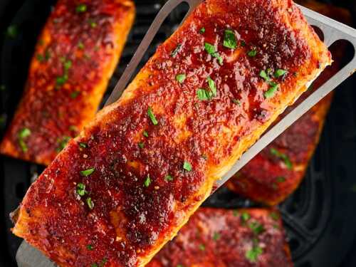 overhead close up view of cooked salmon filled being held over air fryer basket