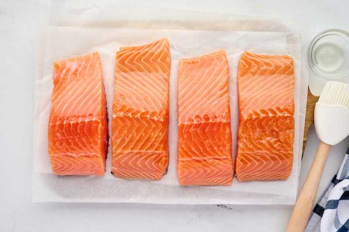 overhead view of four oiled salmon fillets on cutting board
