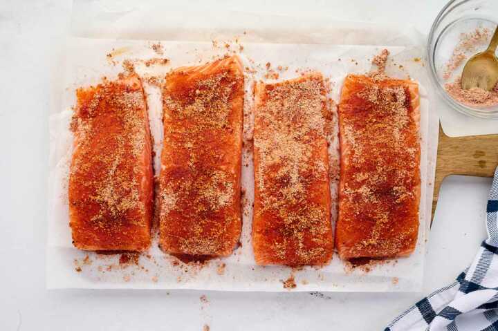 overhead view of four oiled salmon fillets on cutting board rubbed with seasoning mix