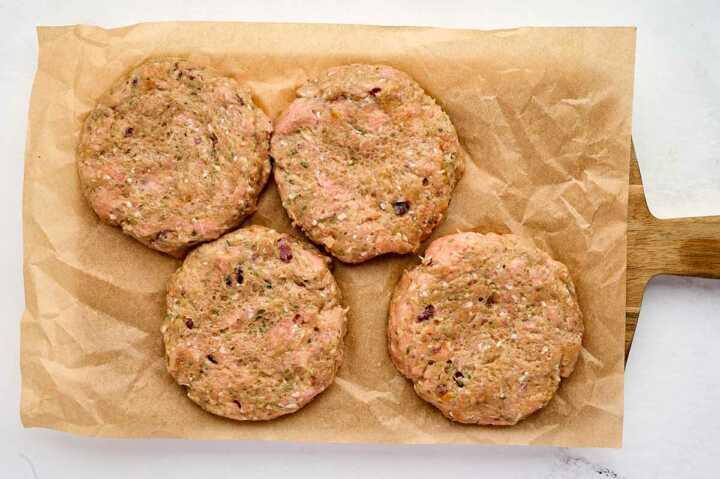 four turkey burger patties on lined cutting board
