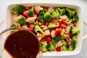 sauce pouring over chicken and vegetables