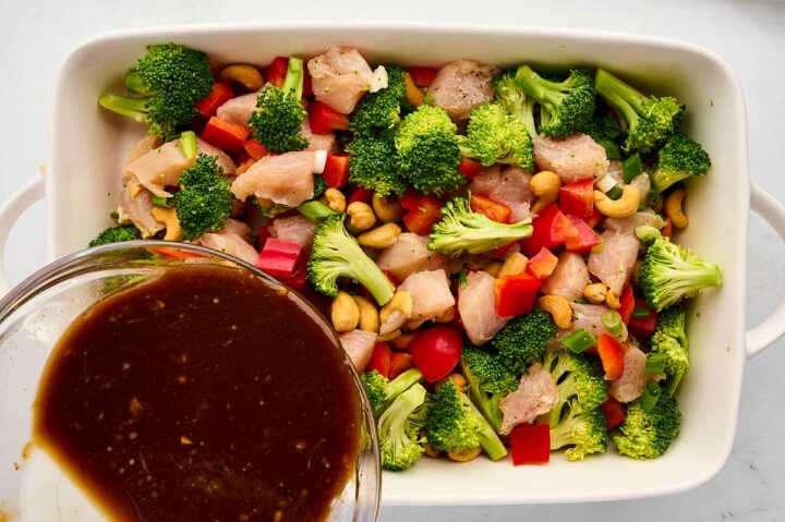 sauce pouring over chicken and vegetables