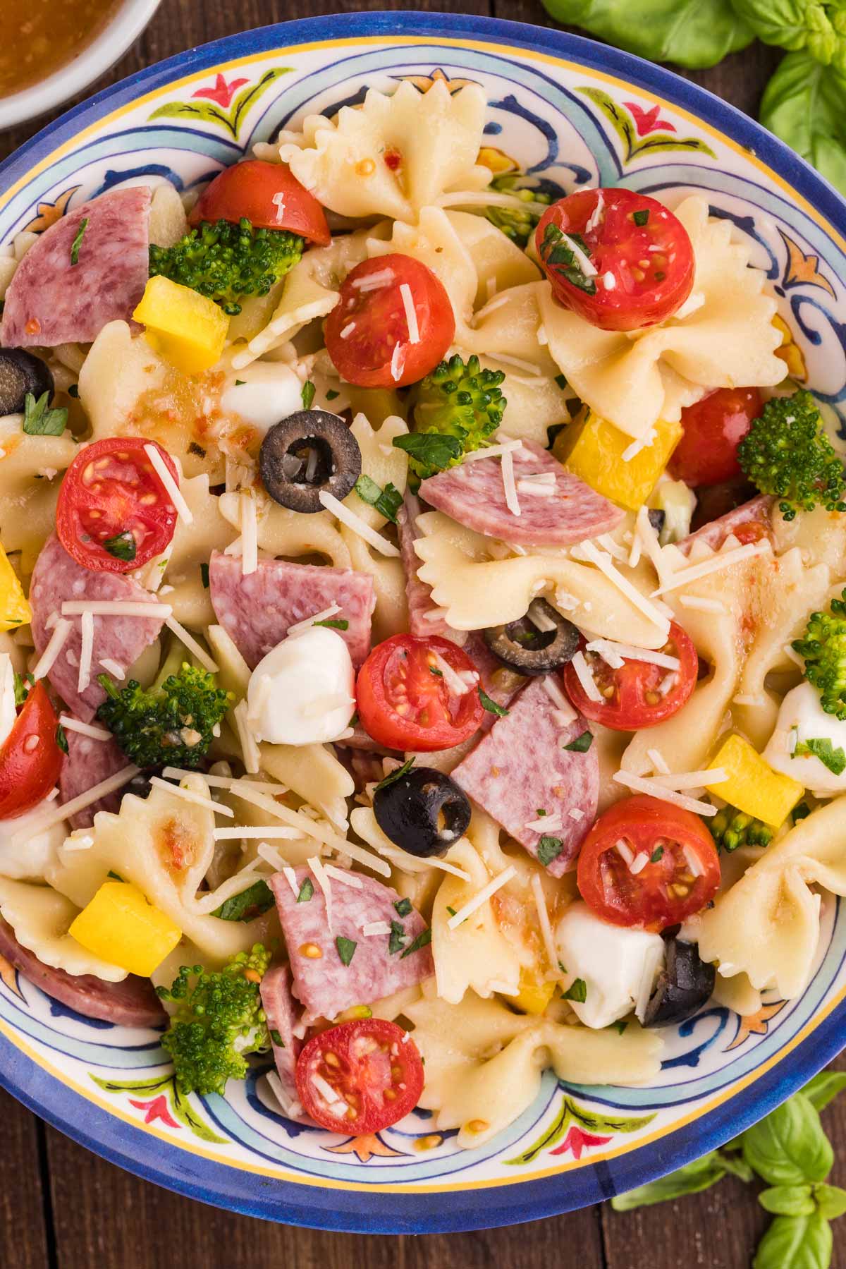 bow tie pasta salad with salami, vegetables, and cheese in colorful bowl