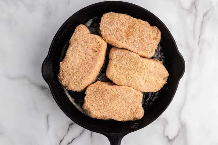 unbaked pork chops on cast iron pan
