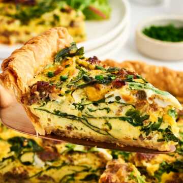 slice of sausage spinach quiche being lifted from pan