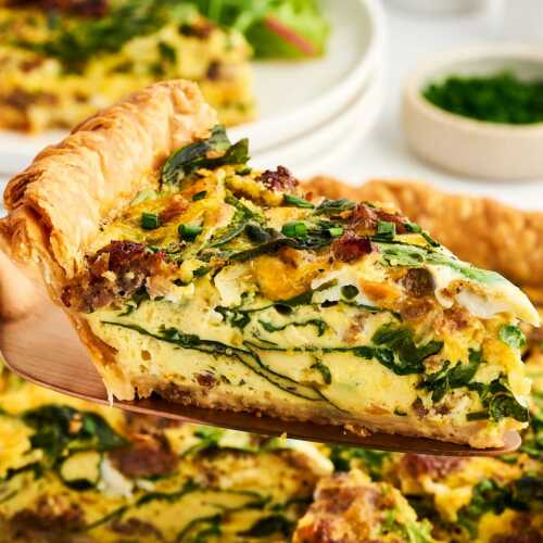 slice of sausage spinach quiche being lifted from pan