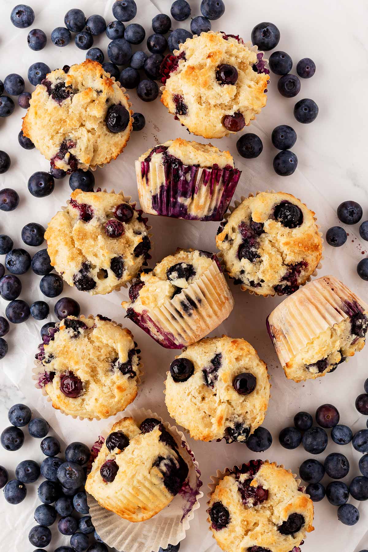 sour cream blueberry muffins on counter with fresh blueberries