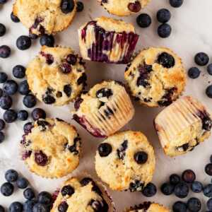 sour cream blueberry muffins on counter with fresh blueberries