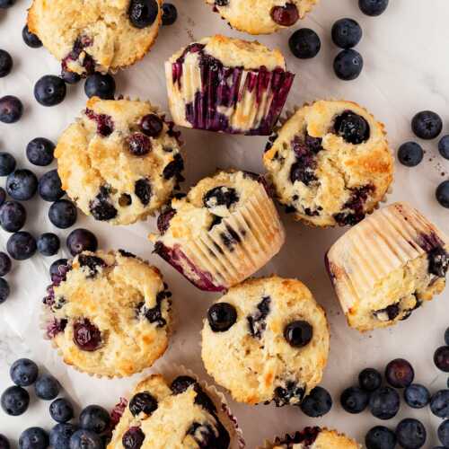 sour cream blueberry muffins on counter with fresh blueberries