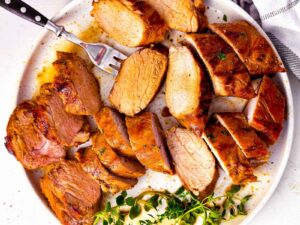 overhead view of sliced pork tenderloin on white plate with fork