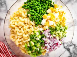 overhead view of ingredients for tuna macaroni salad in clear glass bowl