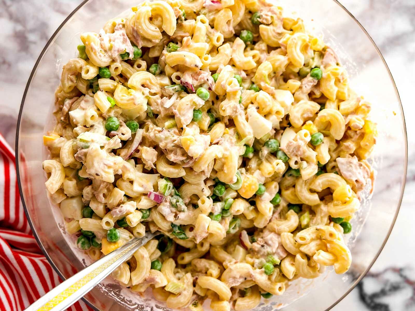 overhead view of mixed tuna macaroni salad in clear glass bowl