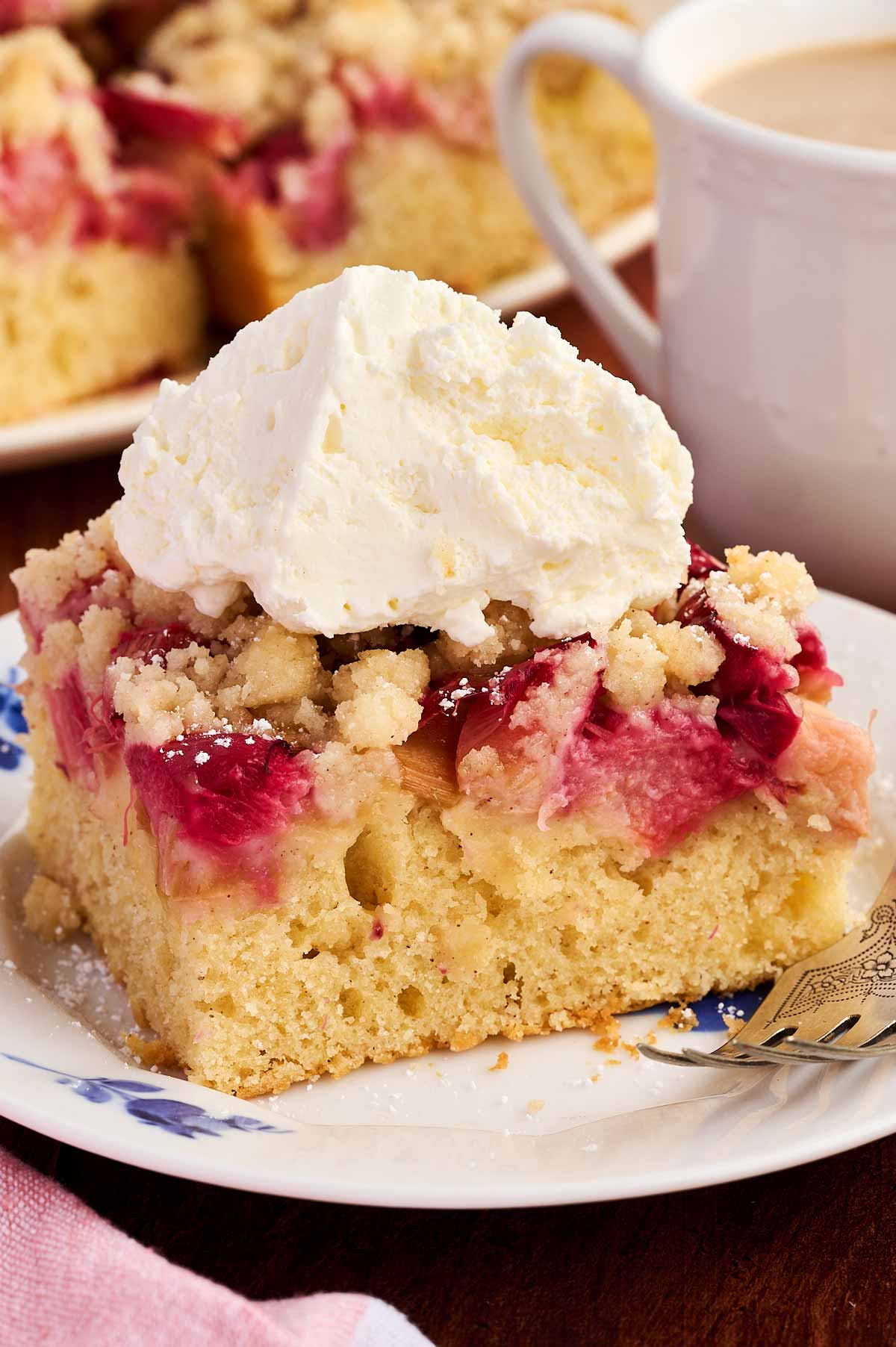 slice of rhubarb coffee cake on plate garnished with whipped cream
