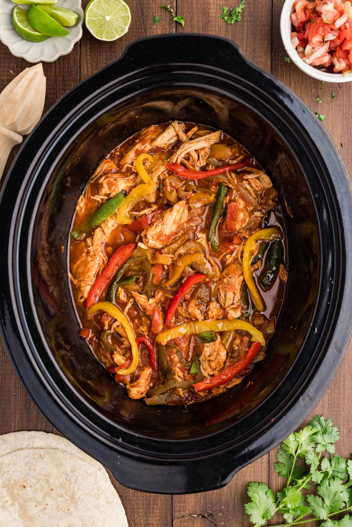 chicken fajitas in crock with toppings and sides around