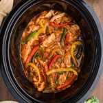 chicken fajitas in crock with toppings and sides around