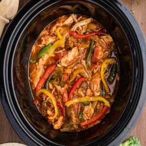 chicken fajitas in crock with toppings and sides around
