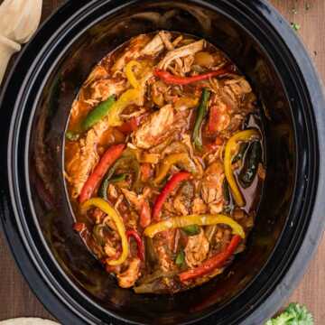 chicken fajitas in crock with toppings and sides around