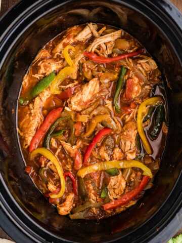 chicken fajitas in crock with toppings and sides around