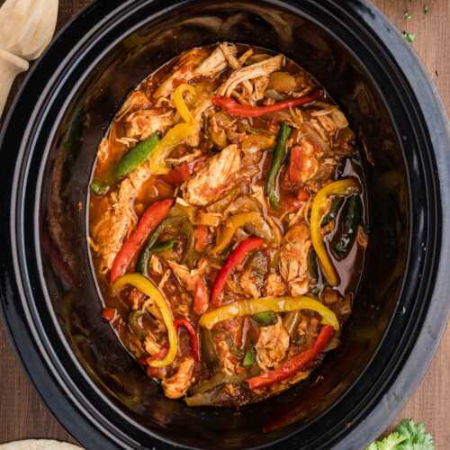 chicken fajitas in crock with toppings and sides around