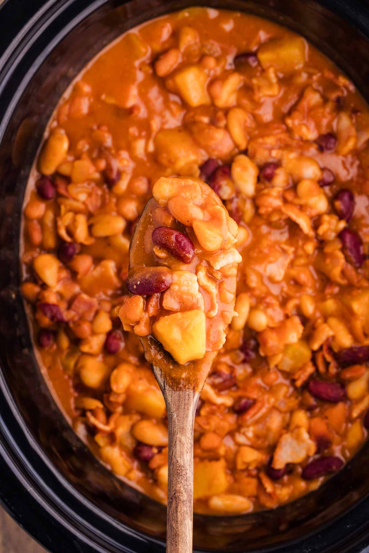 scooping baked beans from slow cooker