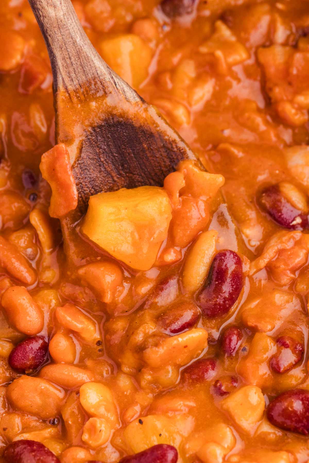 close up of pineapple bbq slow cooker baked beans on spoon