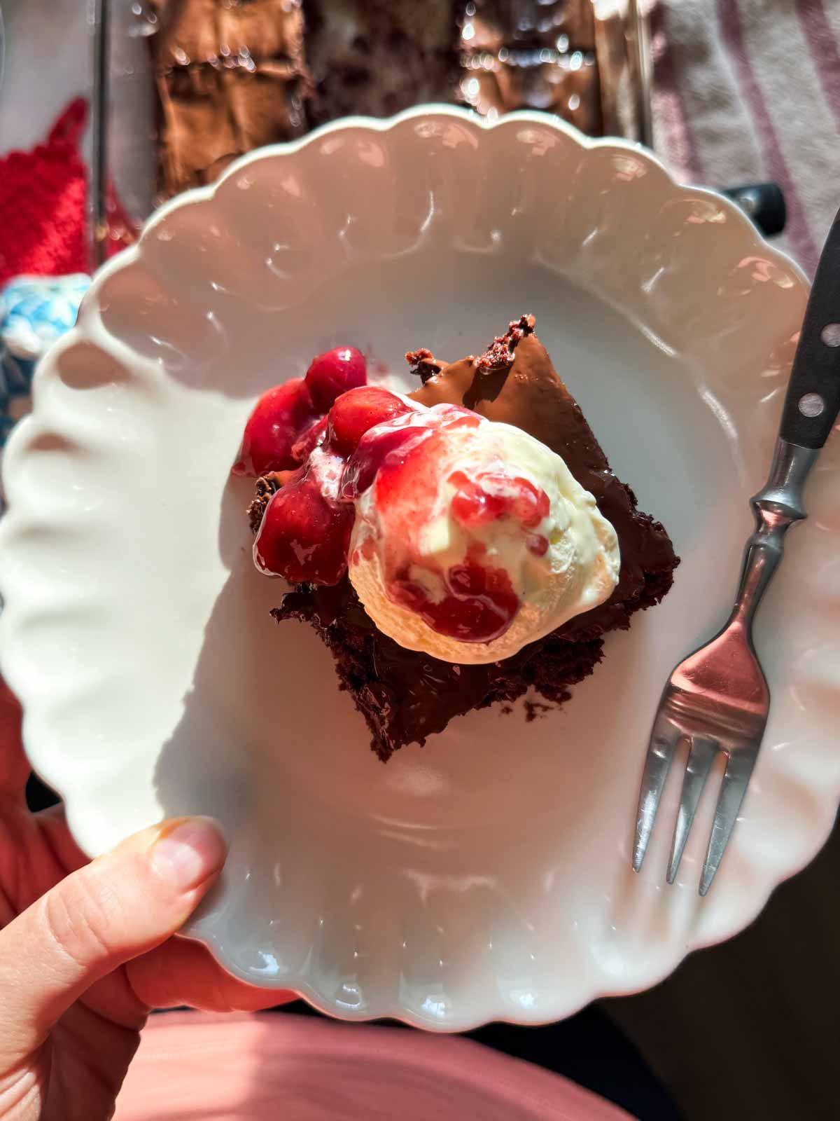 holding a plate with a cherry brownie sundae