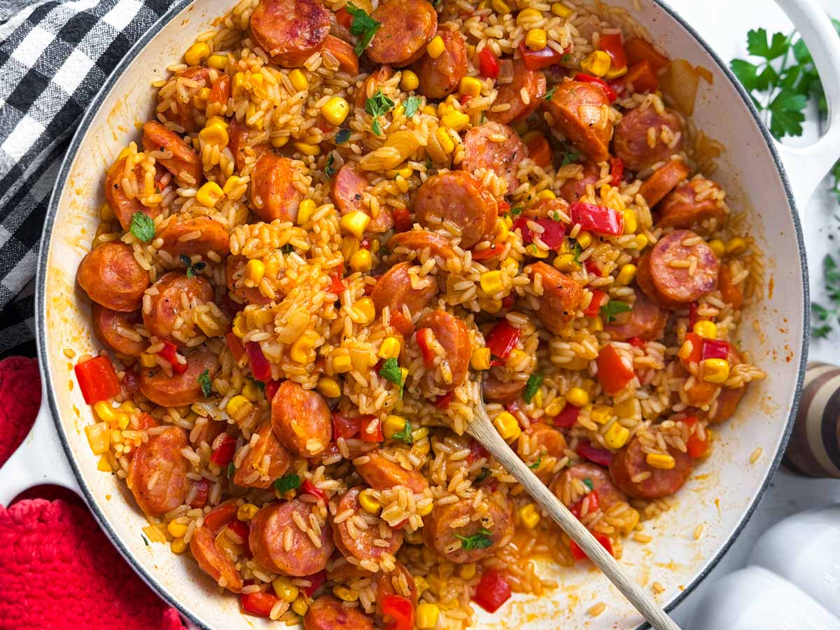 rice and sausage skillet being served with fresh herbs