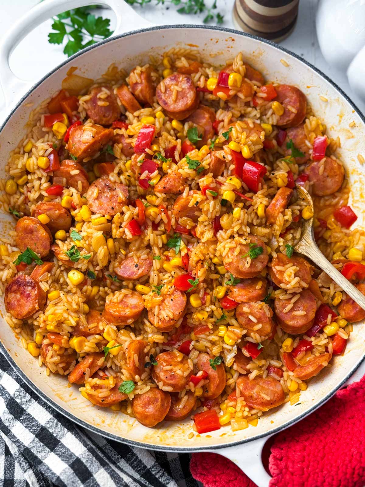 skillet kielbasa and rice being served with fresh herbs