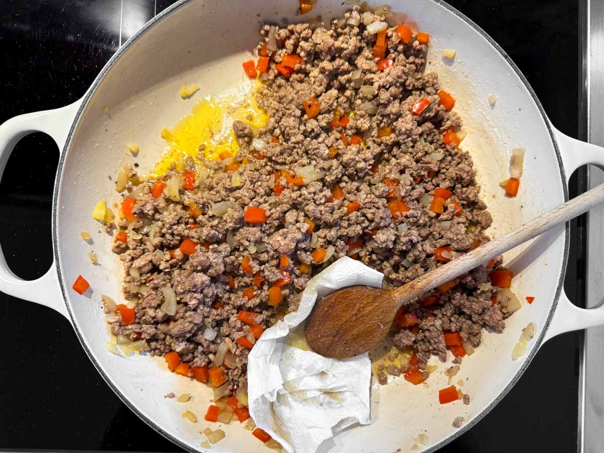 browned sausage and vegetables being drained