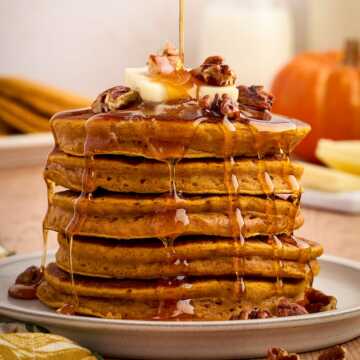 stack of pumpkin pancakes with syrup pouring over