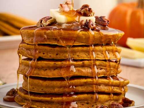stack of pumpkin pancakes with syrup pouring over