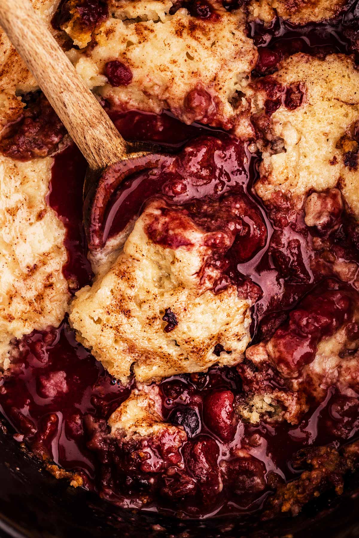 spooning up berry cobbler from the slow cooker